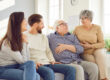 Adult children sitting on couch with senior parents smiling